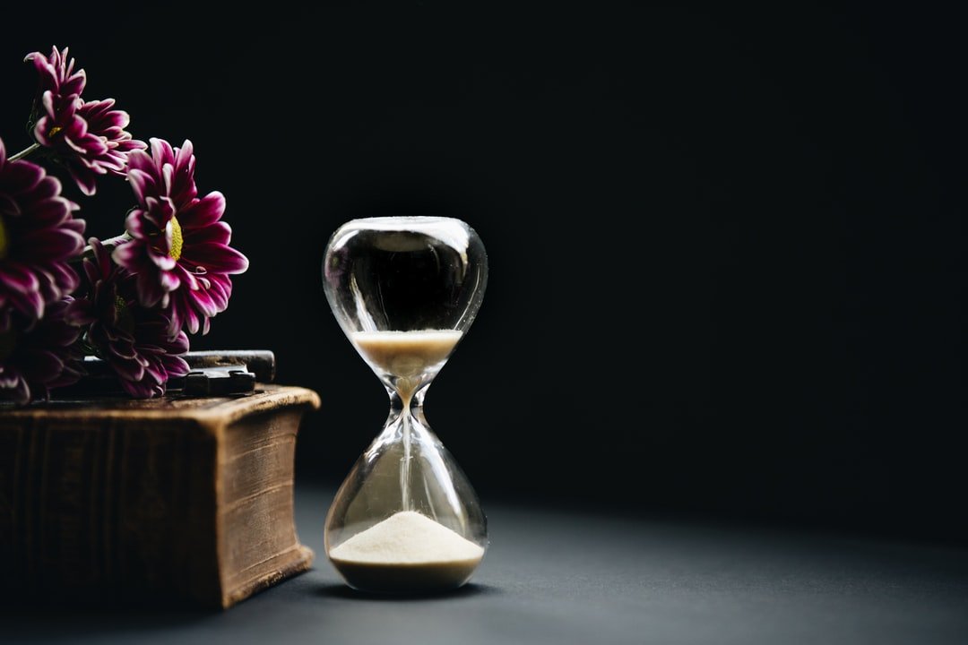 glazen zandloper met bloemen en boek