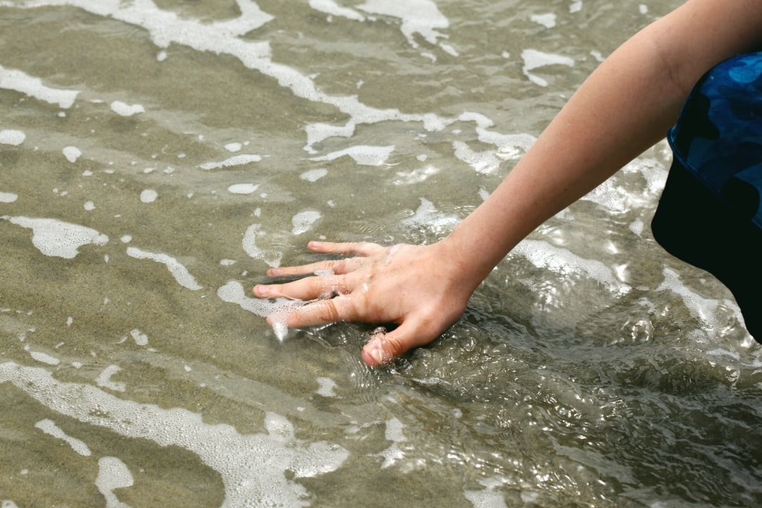 jongen die stromend water aanraakt met hand